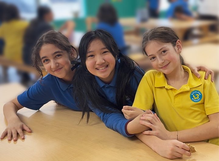 3 happy girls sitting together in the cafeteria.