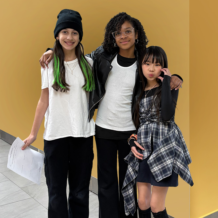 3 girls in trhe hallway in front of a yellow wall.